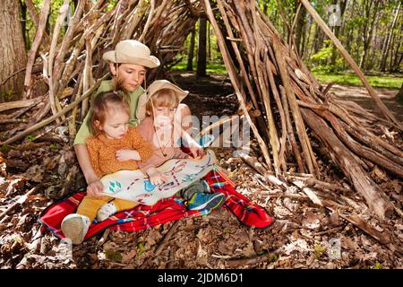 Drei Kinder sitzen mit Schatzkarte spielen Schatzsuche Stockfoto