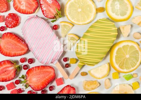 Zwei Eiscremes auf einem Stock - Erdbeere und Zitrone auf weißem Hintergrund. Sommerliche Fruchtdesserts Stockfoto