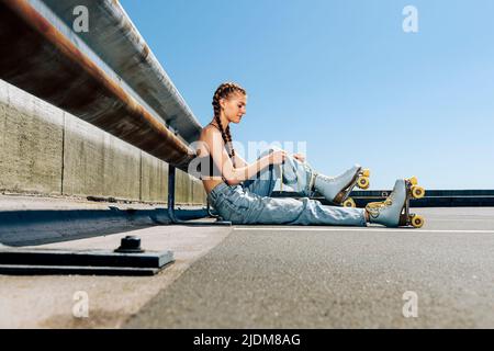 Mädchen binden ihre Rollschuhe, städtischen Hintergrund Stockfoto