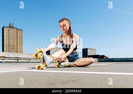 Mädchen binden ihre Rollschuhe, städtischen Hintergrund Stockfoto