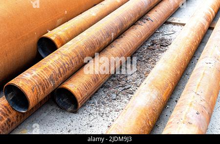 Mit Rost überzogene Metallrohre liegen auf der Baustelle. Bauarbeiten im Gange Stockfoto