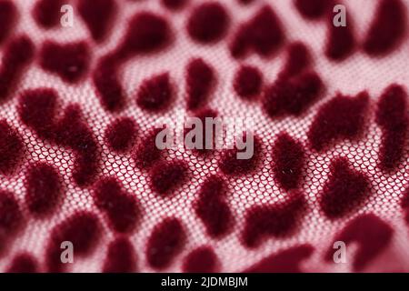 Rotes transparentes Gewebe-Mesh mit Leopardendruck-Hintergrund Stockfoto