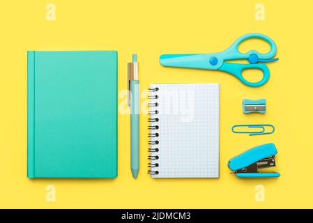 Draufsicht auf Notizblock, Schulbedarf und Spiralnotepad mit Platz für Text auf gelbem Hintergrund. Zurück zum Schulkonzept Stockfoto