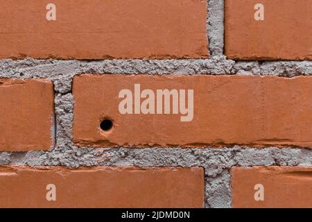 Gebohrter Lochkreis in brauner Ziegelwand Nahaufnahme Reparatur Gebäudekonzept Renovierung. Stockfoto