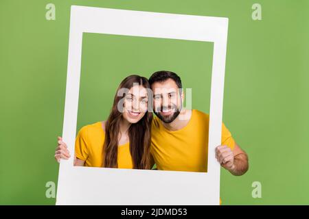 Foto von zwei fröhlichen netten Partnern Hände halten Papier Album Set Karte isoliert auf grünem Hintergrund Stockfoto