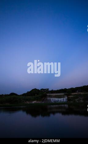 Baumreihe in Silhouette bei Sonnenuntergang, blaue Stunde im Lalbagh Botanical Garden Lake, Bengaluru, Karnataka, Indien. Stockfoto