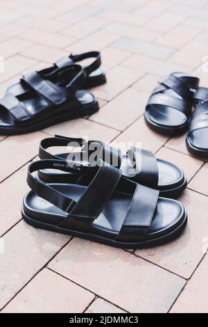 Schwarze Leder-Sandalen für Herren stehen auf einem isolierten Hintergrund. Sommerkollektion mit Herrenschuhen Stockfoto