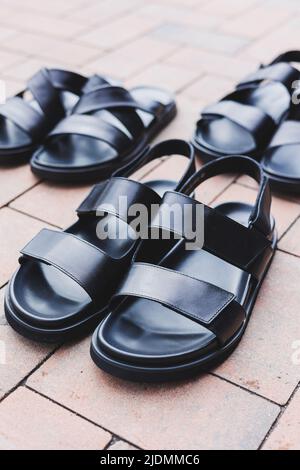 Schwarze Leder-Sandalen für Herren stehen auf einem isolierten Hintergrund. Sommerkollektion mit Herrenschuhen Stockfoto