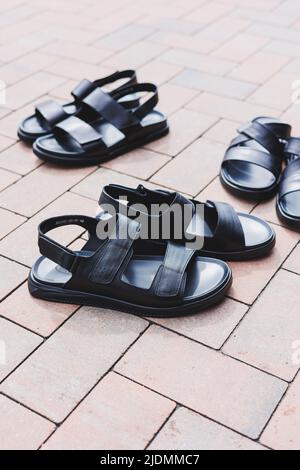 Schwarze Leder-Sandalen für Herren stehen auf einem isolierten Hintergrund. Sommerkollektion mit Herrenschuhen Stockfoto