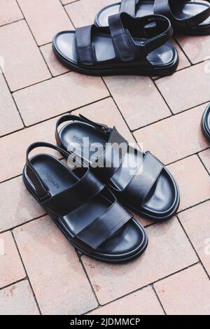 Schwarze Leder-Sandalen für Herren stehen auf einem isolierten Hintergrund. Sommerkollektion mit Herrenschuhen Stockfoto