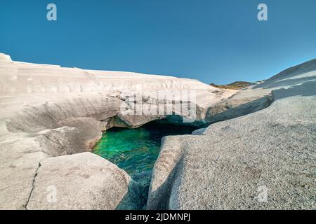 Einzigartige weiße Felsen und smaragdgrünes Wasser in Meereshöhle, Sarakiniko Strand, Insel Milos, Griechenland. Leere Klippen, Sommersonne, klarer blauer Himmel Stockfoto