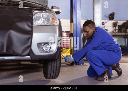 afroamerikanische mittlere Erwachsene weibliche Mechanikerin mit Arbeitswerkzeug während der Reparatur Auto in der Werkstatt Stockfoto
