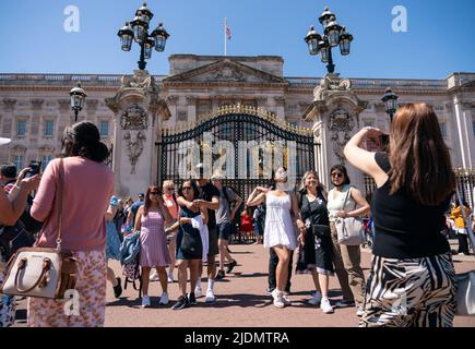 Touristen posieren für Fotos vor dem Buckingham Palace im Zentrum von London, während die Menschen das warme Wetter genießen. Bilddatum: Mittwoch, 22. Juni 2022. Stockfoto