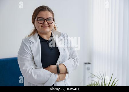Porträt einer Krankenschwester in Uniform, die in der Medizinklinikhalle steht und eine Kamera sucht Stockfoto