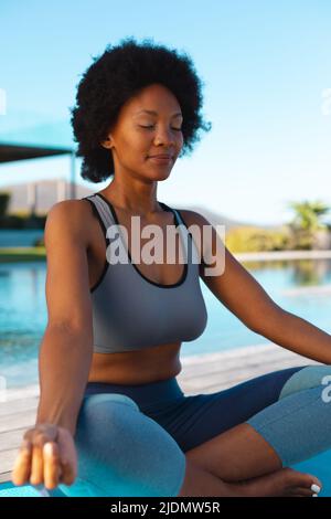Junge afro afroamerikanische Frau meditiert am Pool, Kopierraum Stockfoto