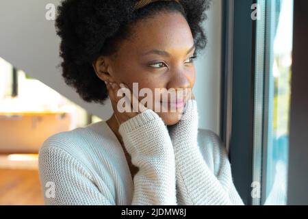 Nachdenkliche afroamerikanische afro junge Frau, die zu Hause wegschaut Stockfoto