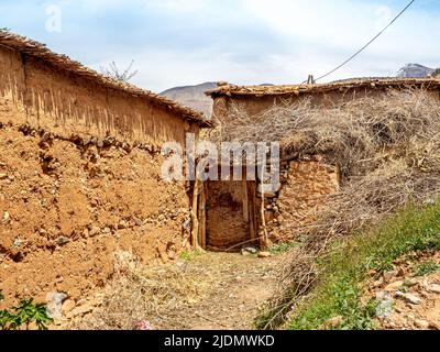 Dorf der Familie Berber mit Mauern aus Steinen und Lehm und Türen, Dächern und Zäunen aus Ästen. Atlasgebirge und blauer Himmel im Bac Stockfoto