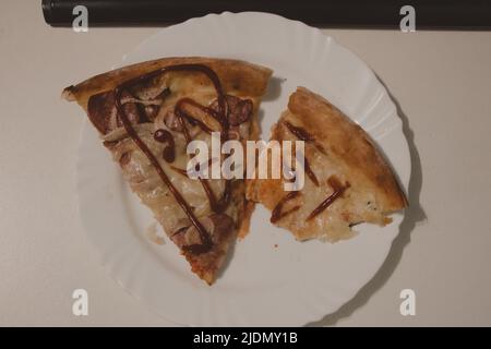 Zwei Scheiben Pizza auf einem weißen Teller Stockfoto