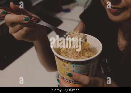 Frau, die Tasse Nudeln isst Stockfoto