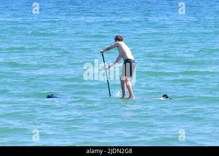 Bournemouth, Dorset, Großbritannien, 22.. Juni 2022, Wetter. Heißer Nachmittag bei herrlicher Sommersonne. Ein Junge auf einem Paddleboard scheint zu sinken. Kredit: Paul Biggins/Alamy Live Nachrichten Stockfoto