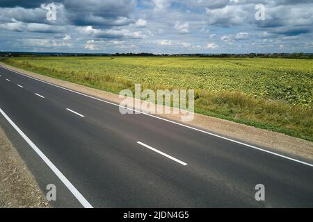 Luftaufnahme einer leeren Intercity-Straße zwischen grünen landwirtschaftlichen Feldern. Draufsicht von der Drohne der Autobahn Stockfoto