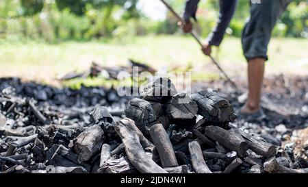 Die Bauern verbrennen Holzkohle aus Holz, das von der Farm abgeschnitten ist. Stockfoto