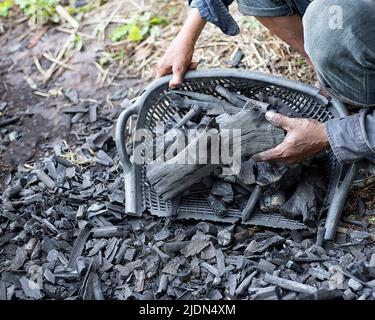 Die Bauern verbrennen Holzkohle aus Holz, das von der Farm abgeschnitten ist. Stockfoto