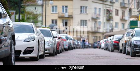 Autos parkten in der Schlange auf der Stadtstraßenseite. Städtisches Verkehrskonzept Stockfoto