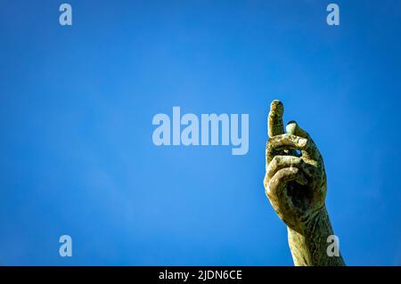 Zeigefinger einer metallenen Hand, die zum Himmel zeigt. Freier Speicherplatz zum Schreiben. Stockfoto