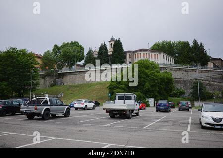 Borgo Val di Taro, Italien - Juni 2022: Kostenlose Parkplätze in einer kleinen italienischen Stadt in der Nähe der alten Stadtmauer und Blick auf den Glockenturm der Kirche Parrocchia Sant Antonino Stockfoto