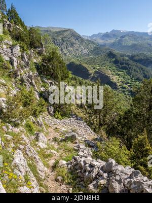 Steiler Pfad oberhalb des Dorfes Tsepelovo in der Zagori-Region Nordgriechenlands mit dem Berg Timfi und dem Gamila-Gipfel in der Ferne Stockfoto