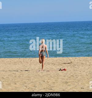 Boscombe, Bournemouth, Dorset, Großbritannien, 22.. Juni 2022, Wetter. Heißer Nachmittag bei herrlicher Sommersonne. Schlanke, attraktive, blonde Frau am Strand, die Stretching-Übungen macht, indem sie auf einem Bein steht. Kredit: Paul Biggins/Alamy Live Nachrichten Stockfoto