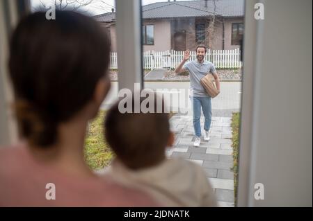 Frau und Sohn warten auf den Mann, der vom Lebensmitteleinkauf nach Hause kommt Stockfoto