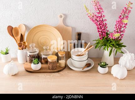 Nahaufnahme von Küchenutensilien und Utensilien aus Holz in einer modernen Küche. Umweltfreundliche Materialien, ohne Kunststoff. Blumen in einem Krug Stockfoto