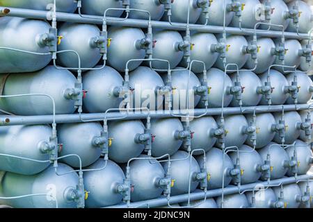 Viele verschiedene kleine Metallflaschen, die mit Gas oder Benzin gefüllt sind, werden in großen Stapeln gestapelt und von der hellen, warmen Tagessonne beleuchtet Stockfoto