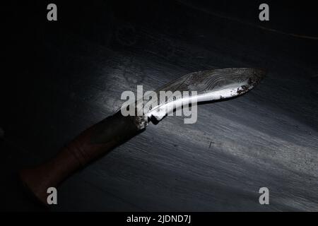 Leuchtendes Kukri-Messer oder nepalesische Machete in dramatischem Licht, Draufsicht. Stockfoto