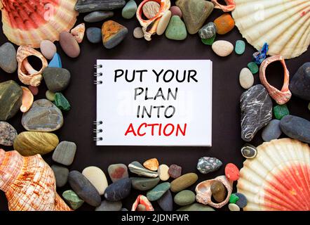 Setzen Sie Ihren Plan in die Tat Symbol. Concept Words setzt Ihren Plan auf einem schönen schwarzen Hintergrund in die Tat um. Seesteine und Muscheln. Unternehmen, die ein Stockfoto