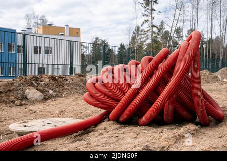 Aufgerolltes rotes PVC-Wellrohr zum Verlegen von Elektrokabeln Stockfoto