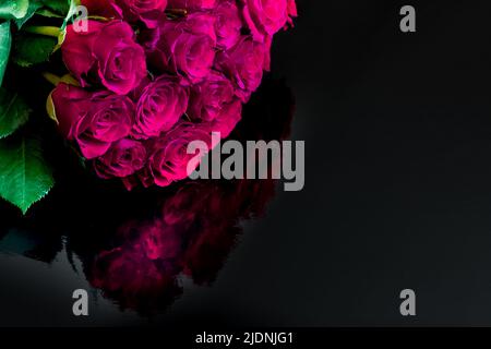 Bouquet von fushia rosa Rosen. Bouquet von fuchsienrosa Rosen auf schwarzem Hintergrund, mit Spiegelung. Stockfoto
