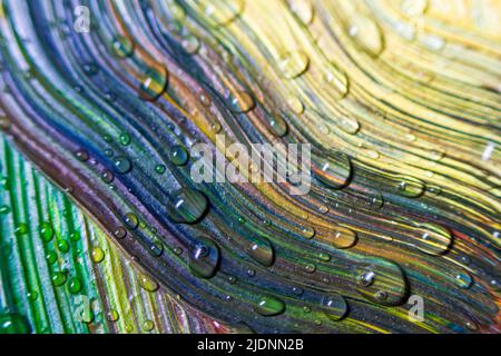 Farbenfrohe, bunte Farben sind mit Wassertropfen bedeckt. Mehrfarbige Abstraktion. Fantastische hypnotische Oberfläche. Nahaufnahme mit abstraktem Muster, Bewegung der flüssigen Farbstruktur mit Wassertropfen. Selektiver Fokus. Stockfoto