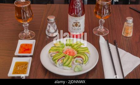 Surimi Maki Sushi mit Avocado und Weingläsern auf einem Tisch in einem japanischen Restaurant Stockfoto