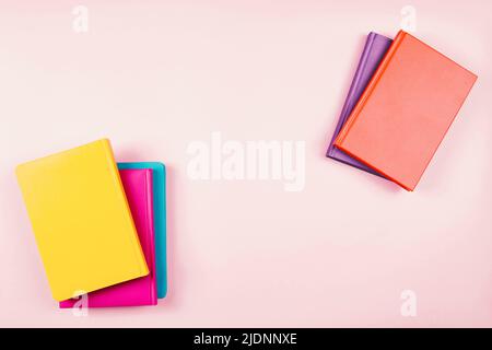 Bunte Hardcover-Bücher auf pastellrosa Hintergrund. Bildung, Selbstlernen, Buchtausch, Buchkreuzungskonzept. Draufsicht, Platz für Text kopieren Stockfoto