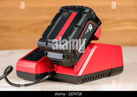 Der Vorgang, bei dem eine Lithiumbatterie von einem kabellosen Bauwerkzeug geladen wird. Der Akku des Schraubendrehers wird im Ladegerät geladen Stockfoto
