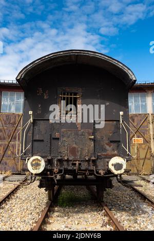 Alte Güterwagen stehen vor dem historischen Lokschuppen. Die Aufnahme wurde bei natürlichem Licht aufgenommen Stockfoto