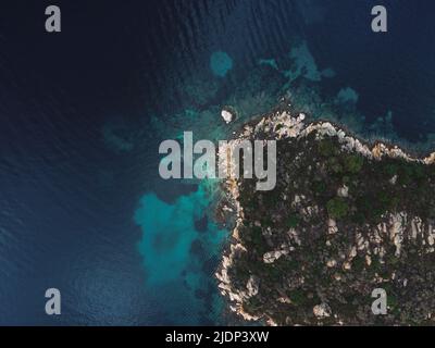Drohnenansicht über einer kleinen Insel mit grüner Vegetation und felsiger Küste im Mittelmeer auf der Halbinsel Chalkidiki, Griechenland. Stockfoto