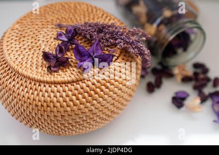 Korbstrohbox Handwerk rund auf der Oberseite mit getrockneten Blumen und Lavendel auf weißem Hintergrund Stockfoto