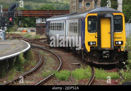 Die Nordzüge der Klasse 156 Supersprinter dmu kommen am Mittwoch, den 22.. Juni 2022, am Bahnhof Carnforth an, und das Unkraut wächst im Gleis. Stockfoto