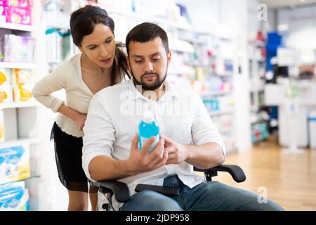 Mann im Rollstuhl und Frau in der Drogerie Stockfoto
