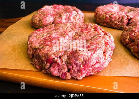 Rohes Hamburger Patty gewürzt mit Pesto und Knoblauch: Nahaufnahme von handgemachten Burger-Patty mit italienischen Gewürzen Stockfoto