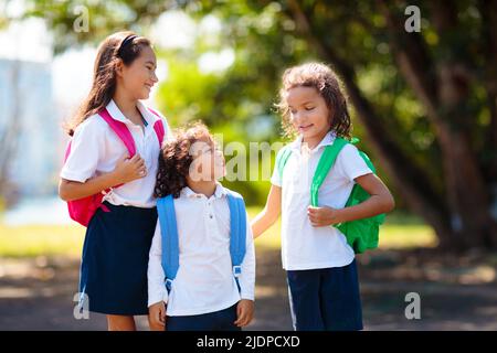 Die Kinder gehen zurück zur Schule. Interrassische Gruppe von Kindern unterschiedlichen Alters laufen und jubeln am ersten Tag des neuen akademischen Jahres. Beginn der Schulferien. Stockfoto